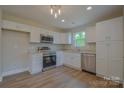 Bright kitchen featuring white cabinetry, stainless steel appliances, granite countertops, and wood-look flooring at 651 S Elm St # 2, Statesville, NC 28677