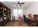 Functional office space with a large bookcase and natural light from the double window at 10240 Superb Ln, Charlotte, NC 28215