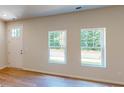 Bright, empty living room with hardwood floors, two large windows, and a white door at 11017 Warfield Ave # 4, Huntersville, NC 28078