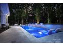 Backyard pool featuring illuminated fountains, in-pool seating, and a patio area perfect for relaxing and entertaining guests at 2418 Shuford Rd, Lincolnton, NC 28092