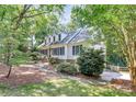 Charming white home featuring black shutters, mature trees, and manicured landscaping at 8500 Peyton Randolph Dr, Charlotte, NC 28277