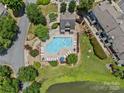 Aerial view of a community pool, surrounded by lounge chairs, greenery, and a nearby pond at 9136 Four Mile Creek Rd, Charlotte, NC 28277