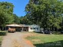 Exterior shot of a tan house featuring a metal carport and a well-kept lawn on a sunny day at 1110 Sulfur Springs Church Rd, Shelby, NC 28152