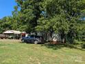 Side view of a tan single-Gathering home with a metal carport surrounded by lush trees at 1110 Sulfur Springs Church Rd, Shelby, NC 28152