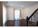 Elegant living room with hardwood floors, crown molding, and large windows dressed with curtains at 12520 Vantage Point Ln, Huntersville, NC 28078