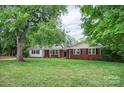 Charming brick home with inviting entryway, black shutters, and beautiful, mature trees at 1538 Hilltop Dr, Shelby, NC 28150