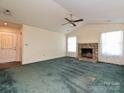 Open living room with a vaulted ceiling, a stone fireplace, a ceiling fan, and large windows offering ample light at 2912 Peachwood Ct, Fort Mill, SC 29715
