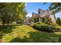 Daytime view of a charming home featuring a covered porch, well-maintained lawn, and lush landscaping at 315 Talon Dr, Salisbury, NC 28147