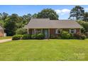 Well-maintained brick home with a green lawn, blue shutters, and mature trees at 416 Park Ave, Granite Quarry, NC 28072