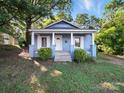 Inviting light blue single-story home with a covered porch, white columns, trimmed windows, and lovely curb appeal at 116 Honeywood Ave, Charlotte, NC 28216