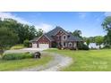 Beautiful two-story brick home with a three-car garage, lush landscaping, and a serene lakeside backdrop at 330 Waters Rd, Salisbury, NC 28146