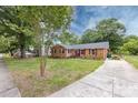 Charming brick home featuring a well-manicured lawn, mature trees, a concrete driveway, and colorful landscaping at 6421 Hidden Forest Dr, Charlotte, NC 28213