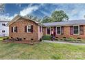 Charming brick home featuring a well-manicured lawn, colorful landscaping, and complementary colored shutters and front door at 6421 Hidden Forest Dr, Charlotte, NC 28213