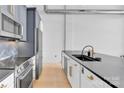 Open kitchen with stainless steel appliances, dark countertops, and white and gray cabinets at 715 N Graham St # 207, Charlotte, NC 28202