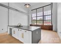 Modern kitchen features a spacious island, stainless steel appliances, and large industrial windows at 715 N Graham St # 207, Charlotte, NC 28202