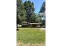 Quaint split-level home with neutral siding and brick accents, nestled amongst lush trees and a green lawn at 12003 Old Beatty Ford Rd, Rockwell, NC 28138