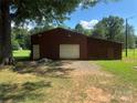 Large outbuilding with a garage door and ample storage space, surrounded by a grassy yard at 12003 Old Beatty Ford Rd, Rockwell, NC 28138