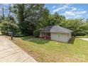A charming single-story home features a well-maintained lawn, complemented by lush, mature trees and a paved walkway at 210 Tuckaseege Rd, Mount Holly, NC 28120