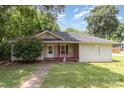 Charming single-story home with a cozy front porch and mature trees in a peaceful residential neighborhood at 210 Tuckaseege Rd, Mount Holly, NC 28120