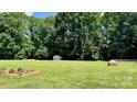 Expansive backyard featuring lush green grass, mature trees, and a storage shed near the wooded area at 2695 Hill Top Dr, Salisbury, NC 28147