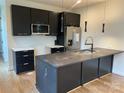 Modern kitchen featuring dark cabinets, stainless steel appliances, and a large island with stone countertop at 3049 Reid Ave, Charlotte, NC 28208