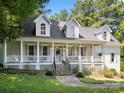 Charming two-story white home with dormer windows and a welcoming front porch, set in a lush, tree-filled landscape at 480 Robinson Rd, Mooresville, NC 28117