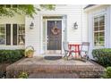 Close-up of the front door entrance with a black door and a small brick porch, adorned with a wreath and seating at 10230 Blackstock Rd, Huntersville, NC 28078