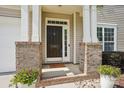 Inviting front porch with brick accents and potted flowers provides a warm welcome at 10303 Dominion Village Dr, Charlotte, NC 28269