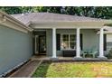 Inviting front porch with stately white columns, neutral brick, black shutters and a green chair set at 13517 Silver King Ct, Huntersville, NC 28078