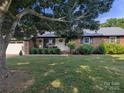Beautiful brick home with lush lawn, decorative bushes, and a welcoming front porch seating area at 3080 Shue Rd, Salisbury, NC 28147
