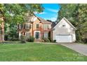 Well-maintained brick home with an attached two-car garage and lush green lawn at 5015 Foxbriar Trl, Charlotte, NC 28269