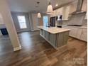 Open kitchen features white cabinets, stainless steel appliances, a large island with a sink, and hardwood floors at 707 Marion Dr, Matthews, NC 28105