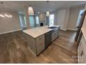 Open kitchen features a large island with sink, stainless appliances, hardwood floors, and connects to living area at 707 Marion Dr, Matthews, NC 28105