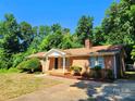 Well-maintained brick home featuring a cozy front porch and mature trees at 125 Circle Dr, Mount Holly, NC 28120