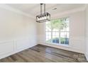 Bright dining room featuring hardwood floors, decorative molding, modern lighting, and a large window with natural light at 14739 Cane Field Dr, Charlotte, NC 28273
