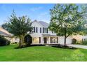 Charming two-story home with black shutters, a well-manicured lawn, and beautiful landscaping around the front at 14739 Cane Field Dr, Charlotte, NC 28273