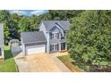 An aerial view of a home with a large driveway, mature trees, and well-kept lawn at 6930 Culloden More Ct, Charlotte, NC 28217