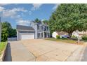 Two-story home with blue siding, two car garage, and long driveway with landscaping at 6930 Culloden More Ct, Charlotte, NC 28217