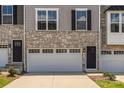 Close-up exterior of townhome featuring stone accents, dark door, and white garage door at 2040 Dornoch Rd, Tega Cay, SC 29708