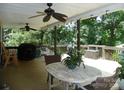 Relaxing back porch with wooden floors, ceiling fans, dining table, grill and hanging swing at 257 Rolling View Dr, New London, NC 28127