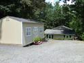 Backyard features large sheds and a house nestled in a lush, green environment with lots of surrounding trees at 257 Rolling View Dr, New London, NC 28127