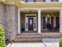 Inviting front porch featuring brick steps, white columns, a decorative front door, and charming rocking chairs at 3113 Beaver Dam Dr # 37, Monroe, NC 28110