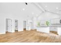 Open-concept kitchen and living area with vaulted ceiling, wood flooring, and white kitchen cabinets at 7 S Coulter Ave, Newton, NC 28658