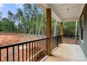 Covered porch with black railing overlooking a wooded backyard at 4615 Yellow Poplar Ln, Concord, NC 28025