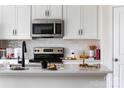 Close up of kitchen island with a stainless steel oven, white subway tile backsplash, and sleek black faucet at 3041 Hutton Gardens Ln, Charlotte, NC 28269