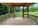 View from a wooden porch with railings, looking out onto a green lawn and trees with a car parked in the driveway at 6581 Emerald Isle Dr, Sherrills Ford, NC 28673