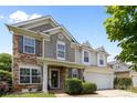 Lovely two-story home featuring stone accents, a covered porch and a two-car garage, with manicured bushes at 10418 Cullen Ct, Charlotte, NC 28278