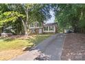 View of the home with an extra long driveway and mature trees at 2508 Wood Star Ct, Matthews, NC 28105
