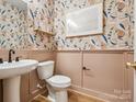 Charming powder room features stylish wallpaper, framed mirror, and pedestal sink at 432 Old Town Village Rd, Waxhaw, NC 28173