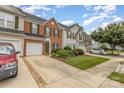 A well-manicured front lawn of a charming townhouse with brick accents, garage and landscaped shrubbery at 4208 Carl Parmer Dr, Harrisburg, NC 28075